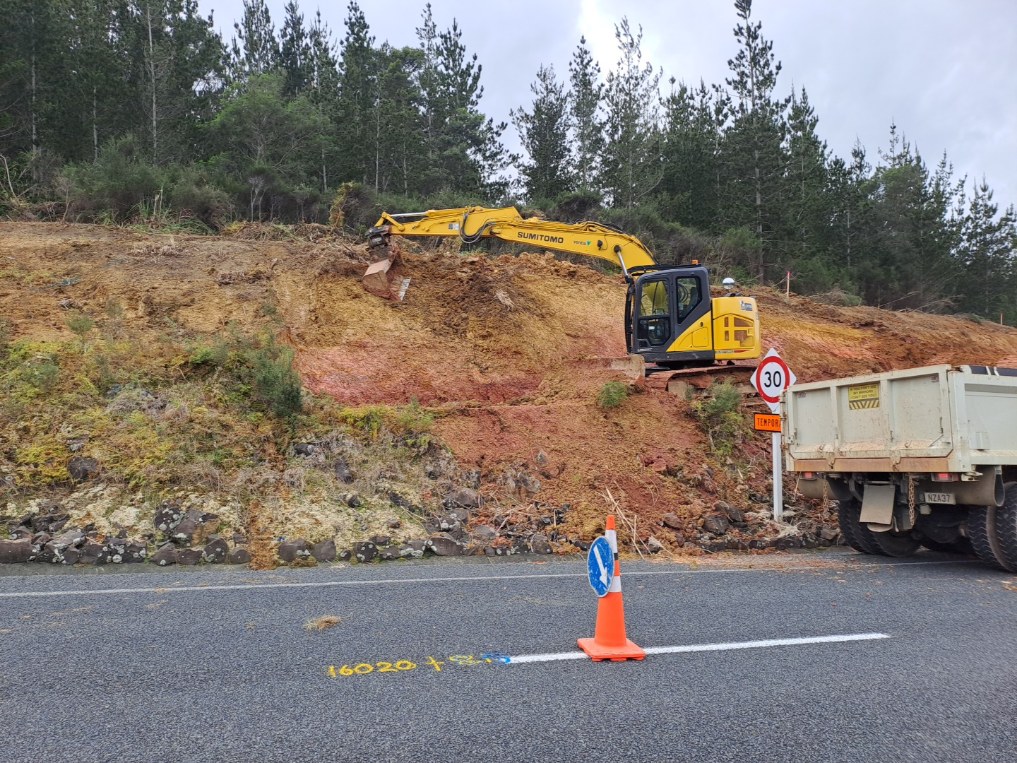 Digger working on Tinopai Road. The digger is on the roadside bank with the road in the foreground